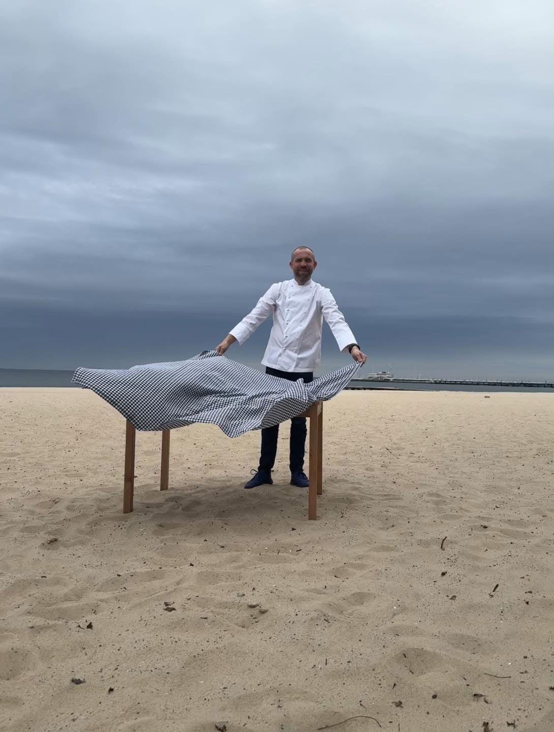 Artur Moroz rozkłada obrus na stole na sopockiej plaży